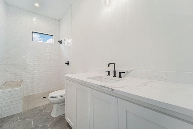 bathroom featuring a tile shower, vanity, tile patterned floors, and toilet