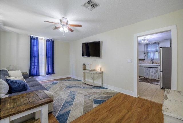 living room with hardwood / wood-style flooring, ceiling fan, lofted ceiling, and a textured ceiling