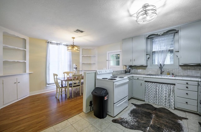 kitchen featuring pendant lighting, sink, white electric range, and plenty of natural light