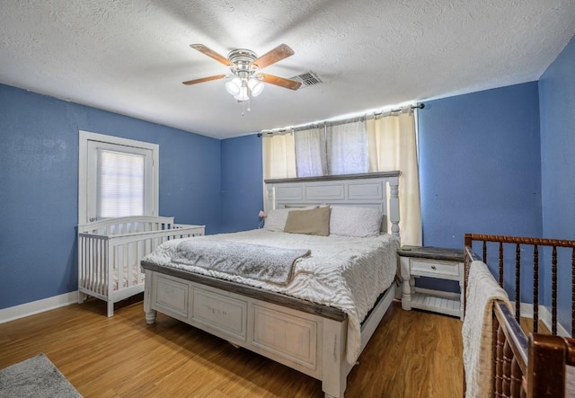 bedroom with ceiling fan, light hardwood / wood-style flooring, and a textured ceiling