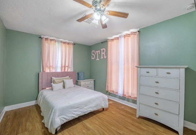 bedroom with ceiling fan, light hardwood / wood-style floors, and a textured ceiling