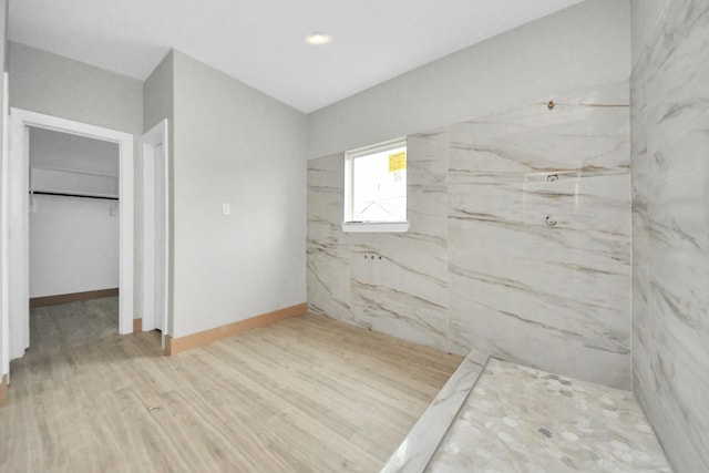 bathroom with wood-type flooring and a tile shower