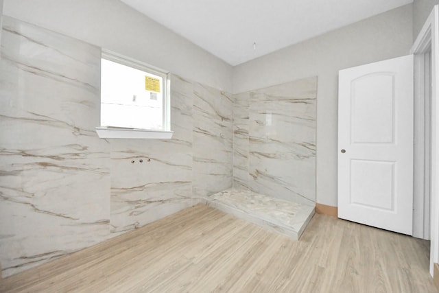 bathroom featuring hardwood / wood-style flooring and a tile shower