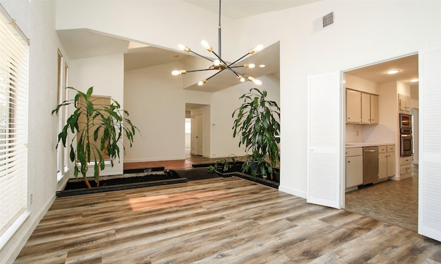 interior space with a notable chandelier, light hardwood / wood-style flooring, and high vaulted ceiling