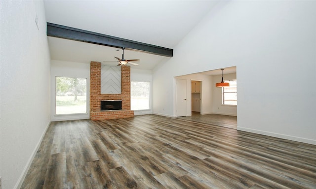 unfurnished living room featuring dark hardwood / wood-style floors, high vaulted ceiling, ceiling fan, a brick fireplace, and beam ceiling