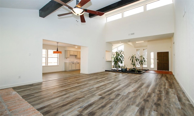 unfurnished living room featuring dark wood-type flooring, ceiling fan, and beam ceiling