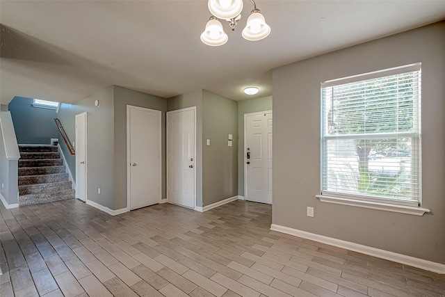 foyer entrance with an inviting chandelier, light hardwood / wood-style floors, and a healthy amount of sunlight