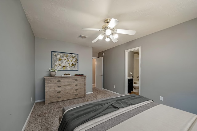 bedroom with ensuite bathroom, light colored carpet, and ceiling fan