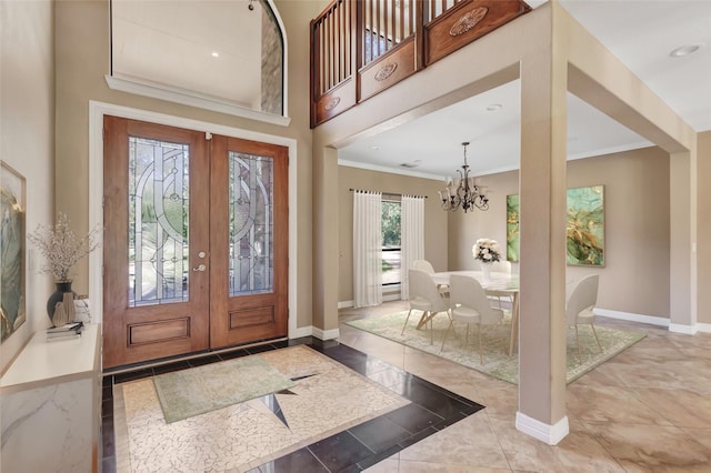 entrance foyer with crown molding, a towering ceiling, a notable chandelier, and french doors