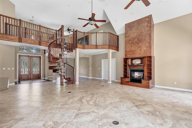 unfurnished living room with high vaulted ceiling, french doors, ceiling fan, and a multi sided fireplace