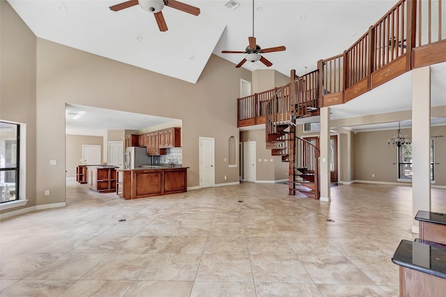 unfurnished living room featuring a high ceiling and ceiling fan with notable chandelier