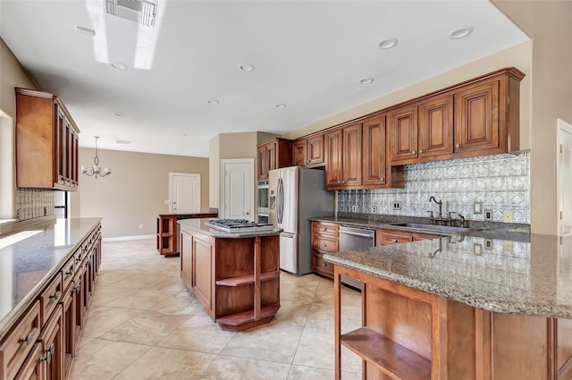 kitchen with sink, tasteful backsplash, dark stone countertops, appliances with stainless steel finishes, and a kitchen island