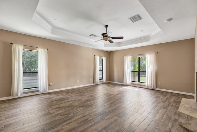 empty room featuring dark hardwood / wood-style flooring, a tray ceiling, ornamental molding, and ceiling fan