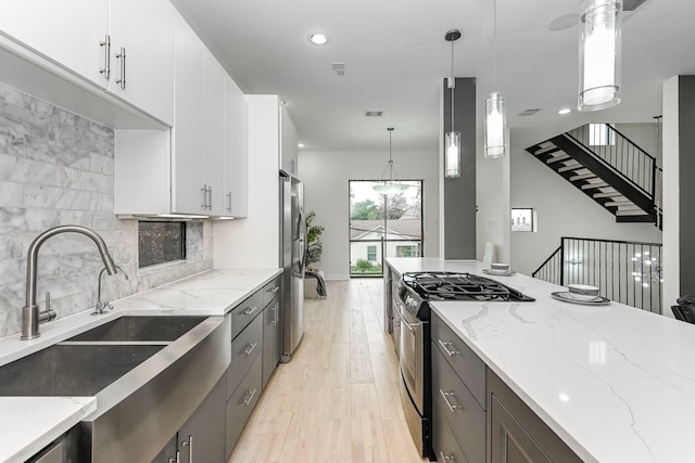 kitchen with decorative light fixtures, stainless steel appliances, decorative backsplash, white cabinets, and light stone countertops