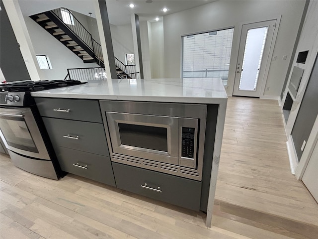 kitchen with stainless steel appliances, light wood-type flooring, recessed lighting, and light stone countertops