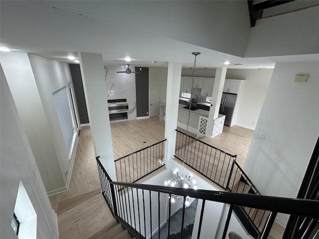 stairway with ceiling fan with notable chandelier, recessed lighting, wood finished floors, and baseboards