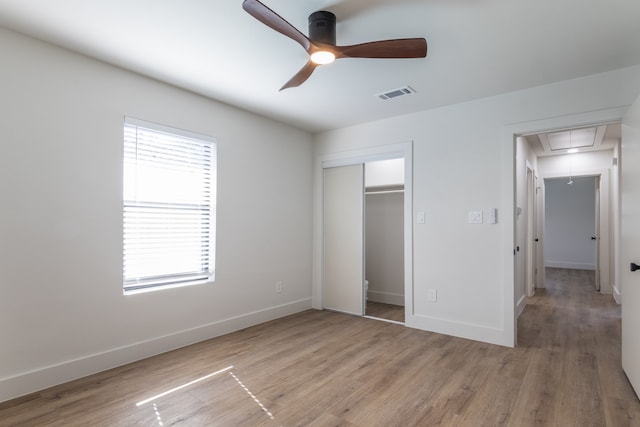 unfurnished bedroom featuring ceiling fan, a closet, and light wood-type flooring