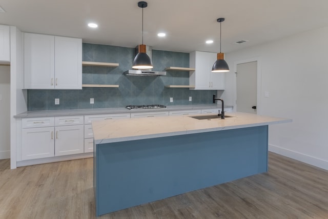 kitchen with white cabinetry, sink, pendant lighting, and wall chimney exhaust hood