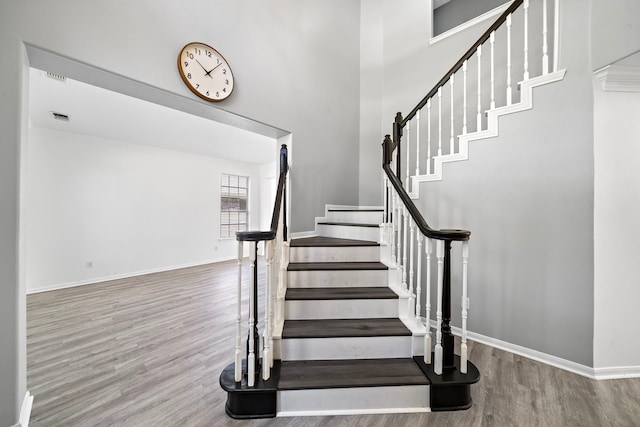 stairway with baseboards, visible vents, and wood finished floors