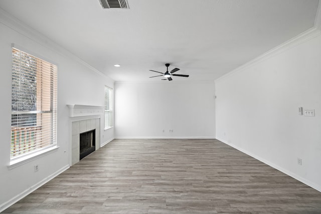 unfurnished living room with wood finished floors, a tile fireplace, visible vents, and crown molding