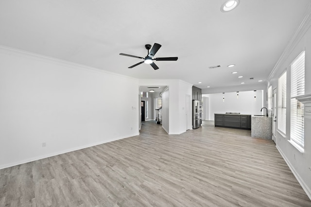 unfurnished living room with baseboards, visible vents, crown molding, and light wood finished floors