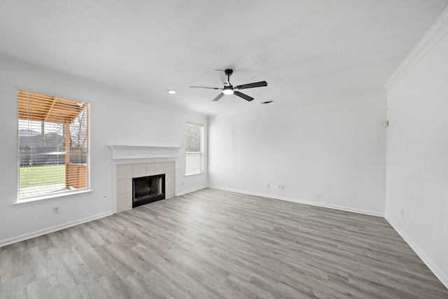 unfurnished living room featuring baseboards, a ceiling fan, a tile fireplace, wood finished floors, and crown molding