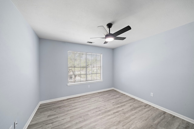 empty room with ceiling fan, a textured ceiling, visible vents, and wood finished floors