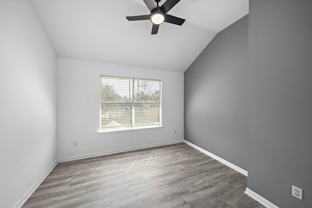 spare room featuring lofted ceiling, ceiling fan, wood finished floors, and baseboards