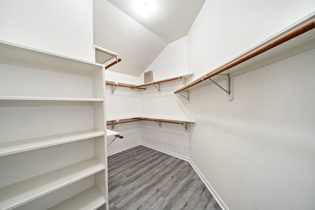 walk in closet with dark wood-type flooring and vaulted ceiling