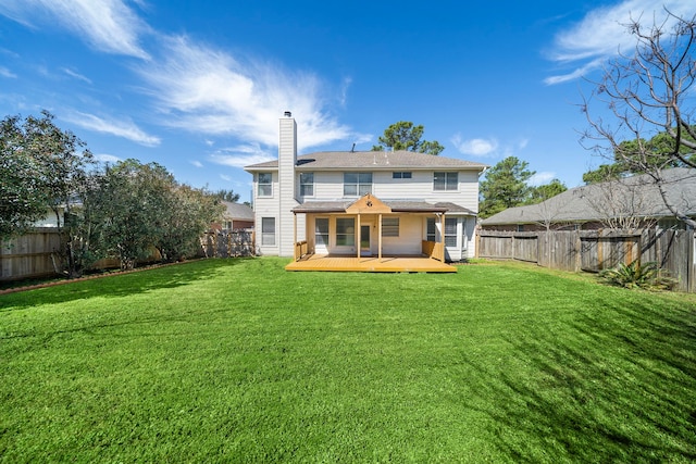 back of house featuring a yard, a chimney, a fenced backyard, and a wooden deck