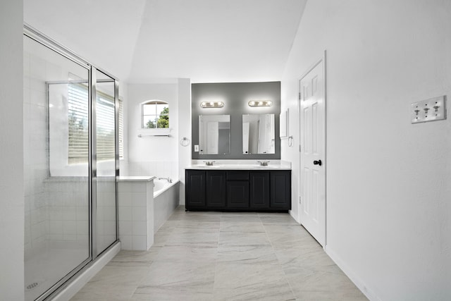 bathroom featuring a stall shower, double vanity, a sink, and a bath