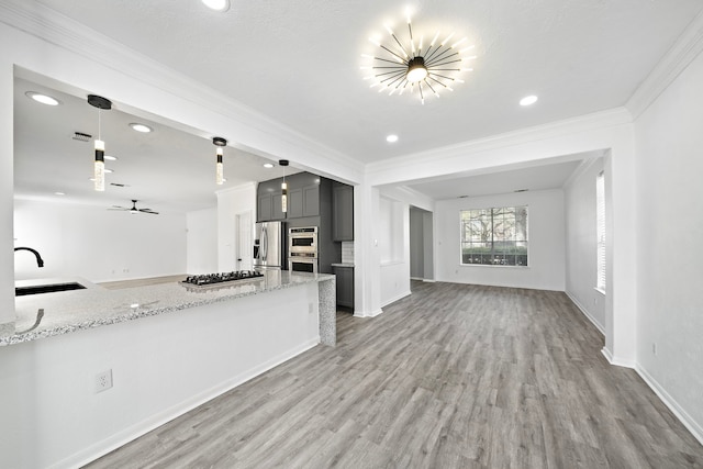 kitchen with open floor plan, appliances with stainless steel finishes, a sink, and crown molding