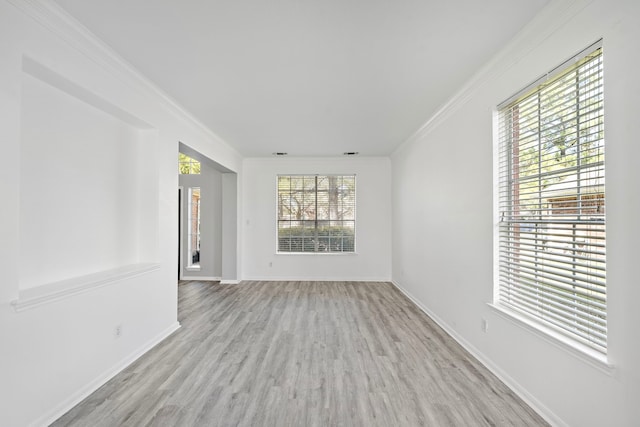 empty room with baseboards, crown molding, and wood finished floors