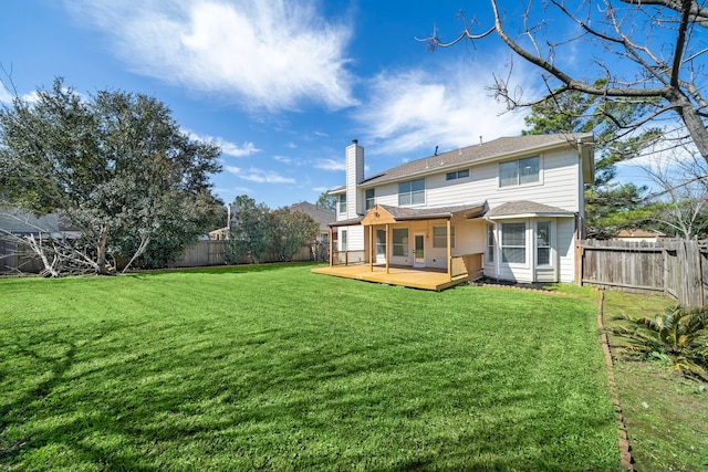 rear view of house featuring a deck, a chimney, a fenced backyard, and a lawn