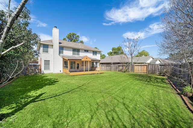 rear view of property featuring a yard, a chimney, a fenced backyard, and a wooden deck