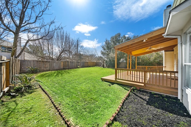 view of yard with a fenced backyard, a deck, and a ceiling fan