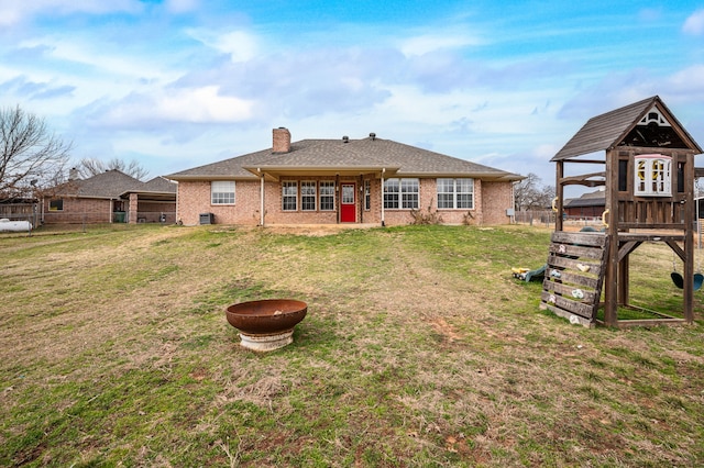 rear view of house with a yard and a playground