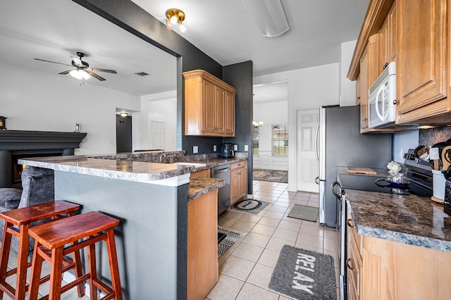 kitchen with light tile patterned flooring, a kitchen breakfast bar, stainless steel dishwasher, kitchen peninsula, and black electric range