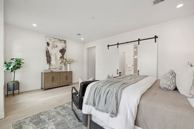 bedroom featuring a barn door and light wood-type flooring