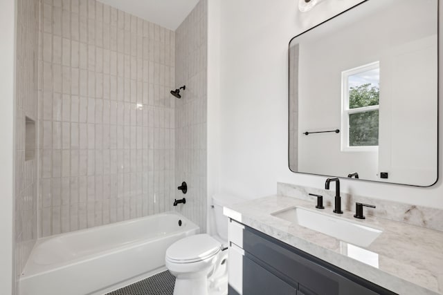 full bathroom featuring tiled shower / bath, vanity, and toilet