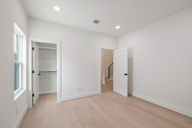 unfurnished bedroom featuring a spacious closet and light wood-type flooring