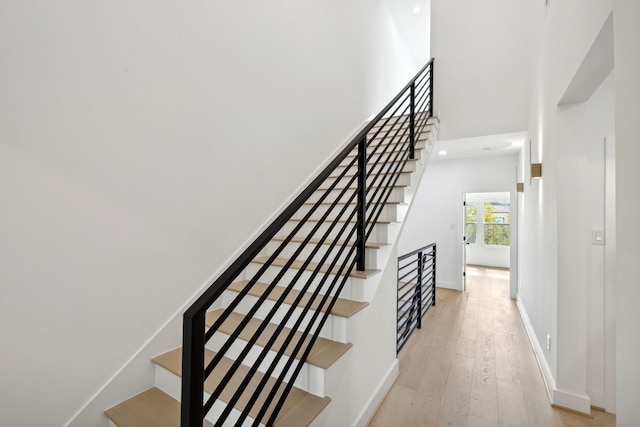 staircase with hardwood / wood-style flooring and a high ceiling