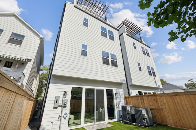 rear view of house featuring central AC unit and a yard