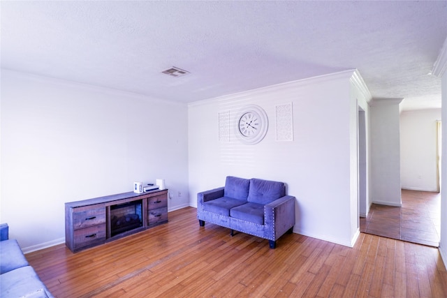 living room featuring crown molding, wood-type flooring, and a textured ceiling