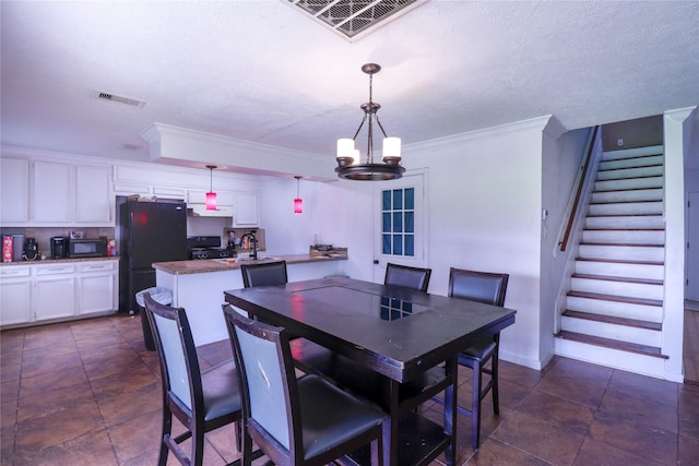 dining room with an inviting chandelier, ornamental molding, and a textured ceiling