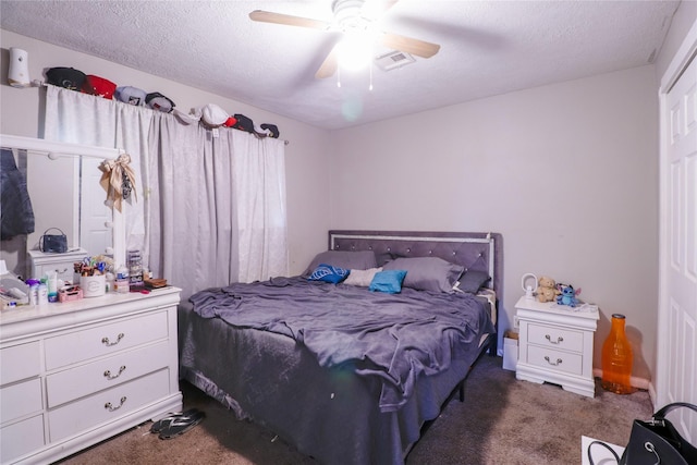 bedroom with ceiling fan, dark carpet, and a textured ceiling