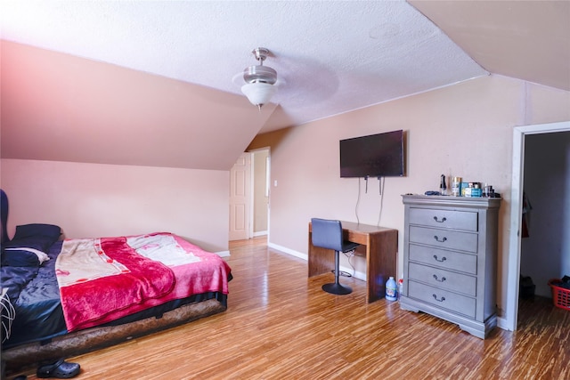 bedroom with hardwood / wood-style flooring, ceiling fan, lofted ceiling, and a textured ceiling