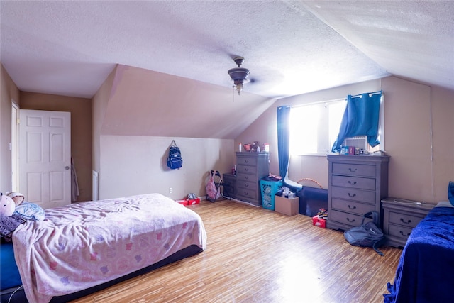 bedroom with vaulted ceiling, ceiling fan, a textured ceiling, and light hardwood / wood-style floors