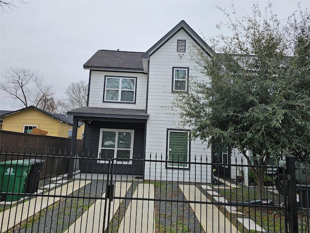 view of front of property with a shingled roof, a fenced front yard, and a gate