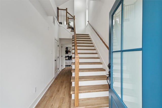 staircase with a towering ceiling and wood-type flooring